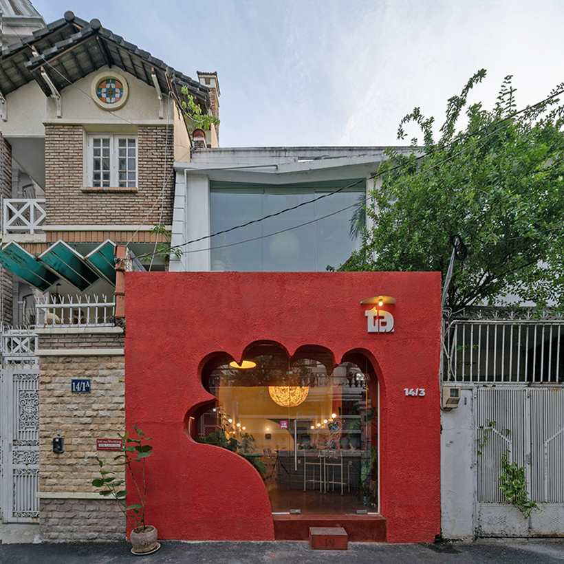 The red facade of the café creates an inviting hand-shaped entrance in Vietnam